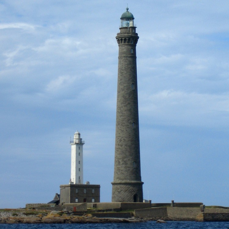 Phare de couleur blanche et grand phare en pierre sur une île.